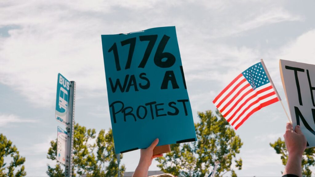 A protest sign being held at Blackstone and Nees avenues in Fresno on Saturday, June 14, 2025 that reads, "1776 WAS A PROTEST." (GV Wire/Eric Martinez)