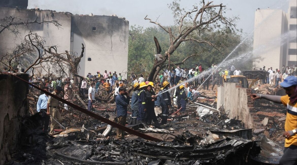 People gather near a damaged building and trees as firefighters work at the site where an Air India plane crashed in Ahmedabad, India, June 12. REUTERS/Amit Dave