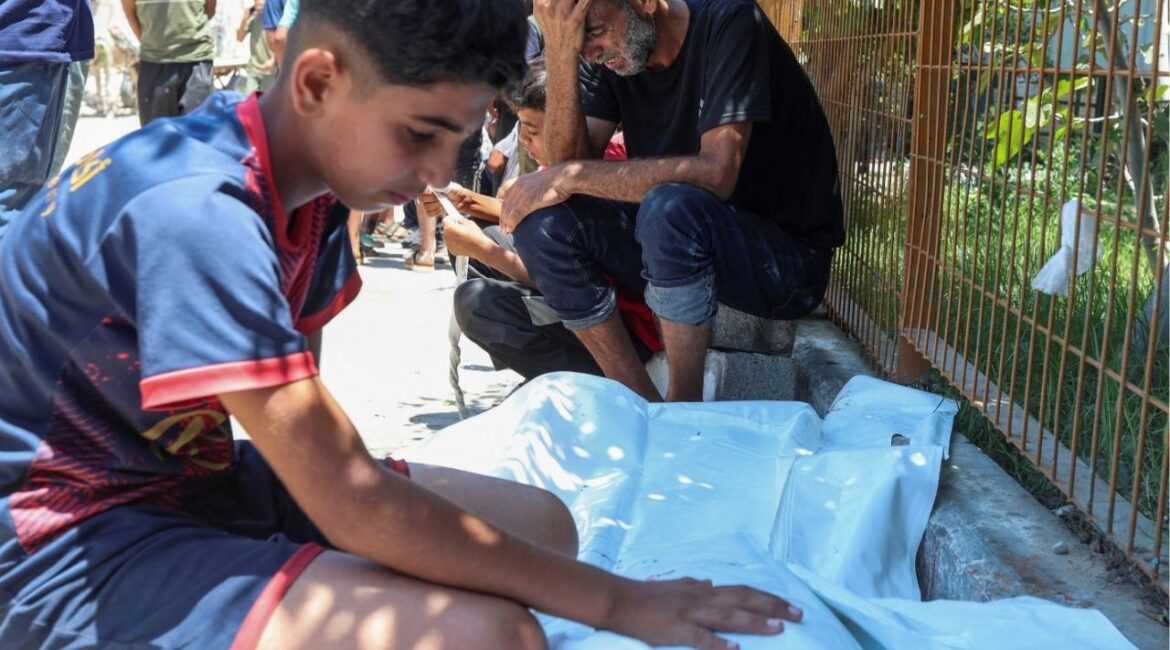 A Palestinian man from the Katoo family, with his son, mourns beside the body of his other son, who was killed by Israeli fire while seeking aid near a distribution point in Rafah, according to medics, at Nasser Hospital in Khan Younis, southern Gaza Strip, July 12, 2025. REUTERS/Ramadan Abed