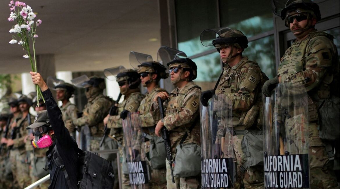 A demonstrator raises his hand holding flowers as members of the National Guard stand in formation outside a federal building during the No Kings protest against U.S. President Donald Trump's policies, in Los Angeles, California, U.S., June 14, 2025. (Reuters File)