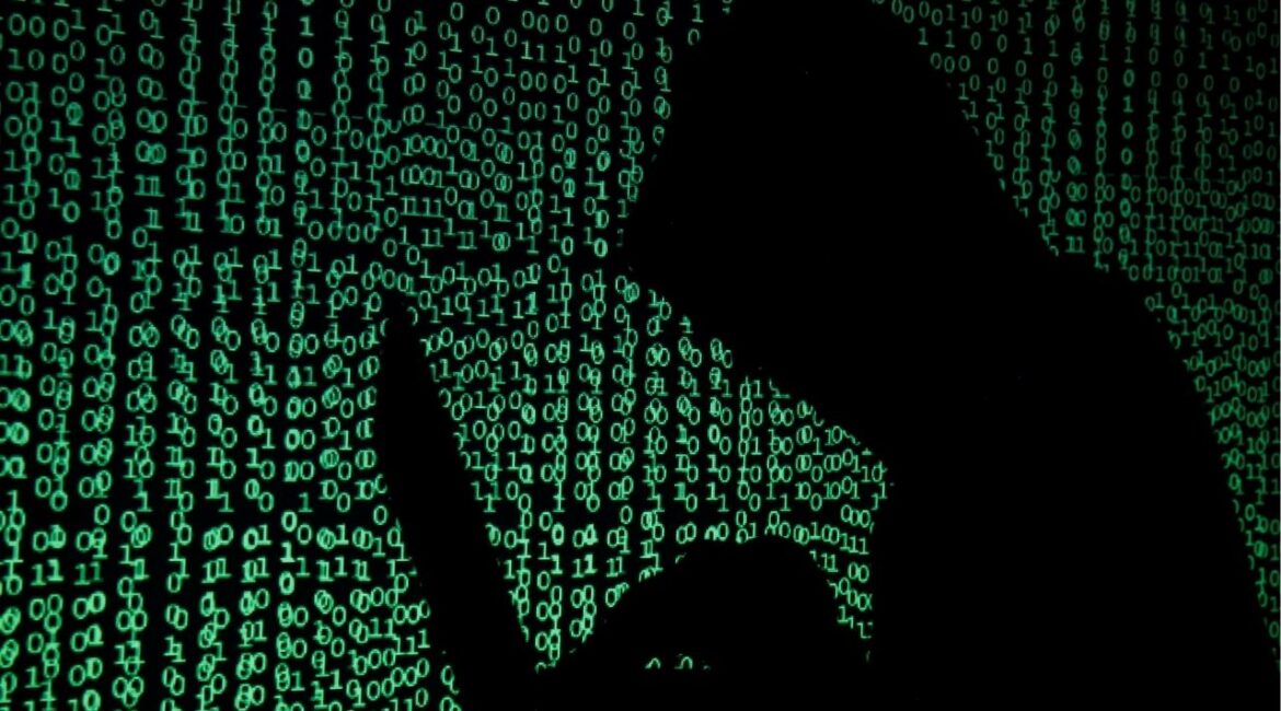 A hooded man holds a laptop computer as cyber code is projected on him in this illustration picture taken on May 13, 2017. (Reuters File)