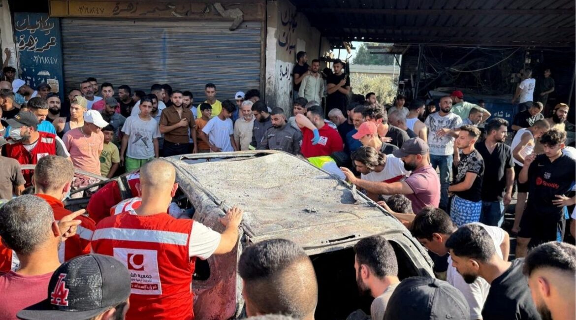 People gather near a damaged car after the Israeli military said in a statement that it struck a "key" figure from Palestinian militant group Hamas, in Ayrounieh, northern Lebanon July 8, 2025. (Reuters/Walid Saleh)