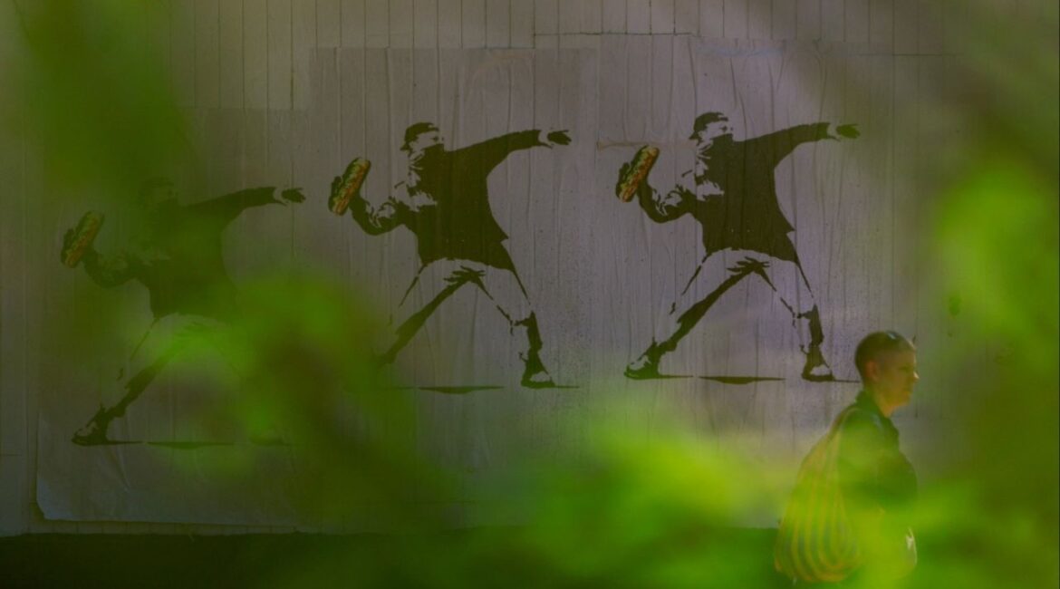 A person walks past signs depicting a man throwing a sandwich, used as a symbol of protest, after U.S. President Donald Trump deployed the National Guard and ordered an increased presence of federal law enforcement to assist in crime prevention, in the Capitol Hill neighborhood, in Washington, D.C., U.S., August 23, 2025. (Reuters File)
