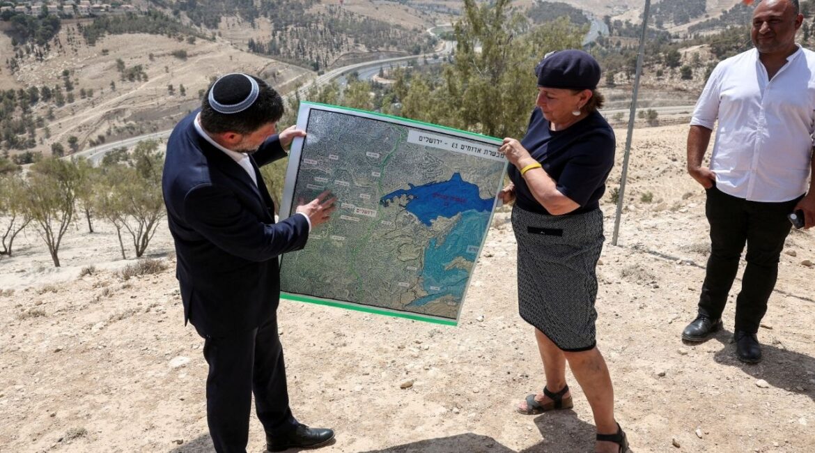 Israeli Finance Minister Bezalel Smotrich and a woman hold a map that shows the long-frozen E1 settlement scheme, that would split East Jerusalem from the occupied West Bank, on the day of a press conference near the Israeli settlement of Maale Adumim, in the Israeli-occupied West Bank, August 14, 2025. (Reuters File)
