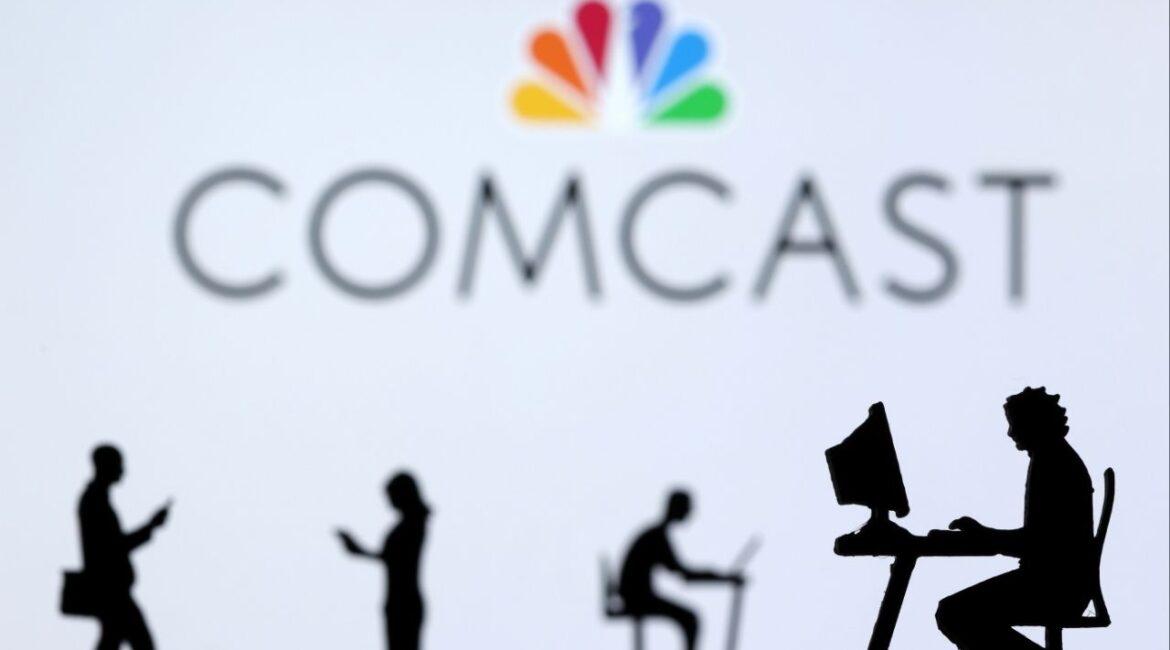 Small toy figures with laptops and smartphones are seen in front of displayed Comcast logo, in this illustration taken December 5, 2021. (Reuters File)