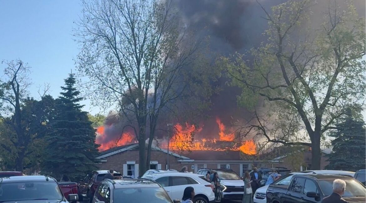People gather at the site as smoke and fire rise, following an incident in which a man crashed his vehicle through the front doors of a Michigan church and opened fire with an assault rifle and set the church ablaze, in Grand Blanc, Michigan, U.S., September 28, 2025, in this screengrab obtained from social media video. Heem Vaniawala/via REUTERS