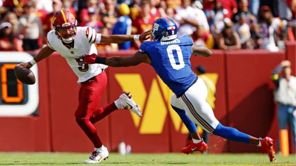 Sep 7, 2025; Landover, Maryland, USA; Washington Commanders quarterback Jayden Daniels (5) runs the ball during the fourth quarter against New York Giants linebacker Brian Burns (0) at Northwest Stadium. (Peter Casey-Imagn Images)