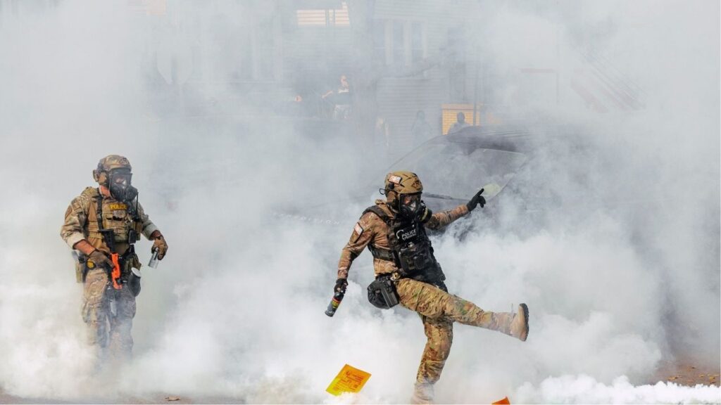 A member of the Border Patrol Tactical Unit, BORTAC, kicks a tear gas canister toward a crowd of people during clashes with community members amid immigration raids in the East Side neighborhood of Chicago, Oct. 14, 2025. A federal judge in Chicago said on Thursday that she was “profoundly concerned” that federal agents might have violated a court order that she had issued setting strict limits on their use of tear gas and requiring them to give protesters warnings to disperse, and also said she would order federal agents to wear body cameras. (Jamie Kelter Davis/The New York Times)