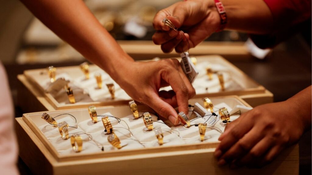 A salesperson shows a gold ring to customers at a jewelry showroom in Ahmedabad, India, October 8, 2025. (Reuters/Amit Dave)