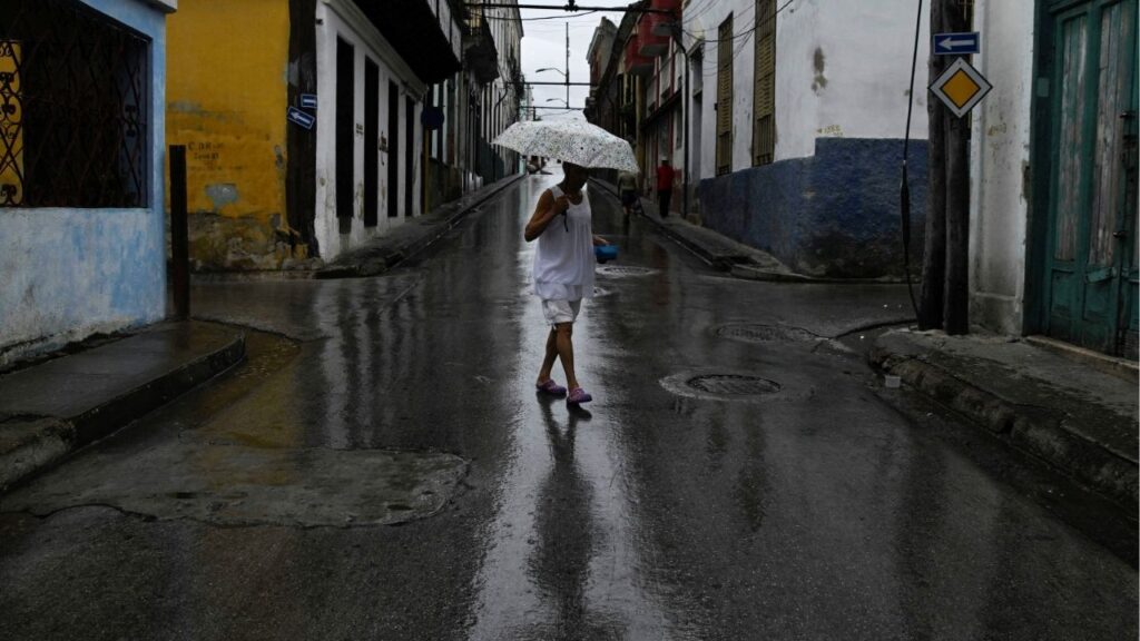A woman holding an umbrella walks across a street ahead of Hurricane Melissa's landfall, in Santiago de Cuba, Cuba, October 28, 2025. (Reuters/Norlys Perez)