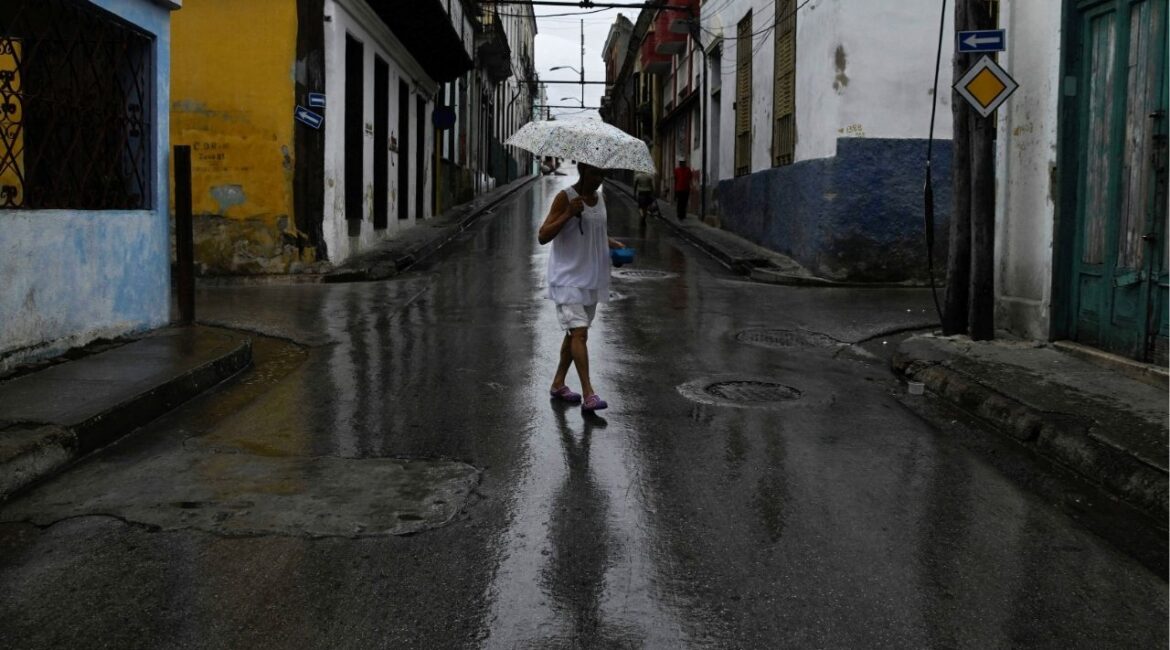 A woman holding an umbrella walks across a street ahead of Hurricane Melissa's landfall, in Santiago de Cuba, Cuba, October 28, 2025. (Reuters/Norlys Perez)