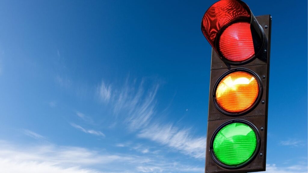 Asset id: 2075708056 Closeup of a traffic light on a blue sky with clouds and copy space, with all three lights on, green, orange and red. Italy, Europe.