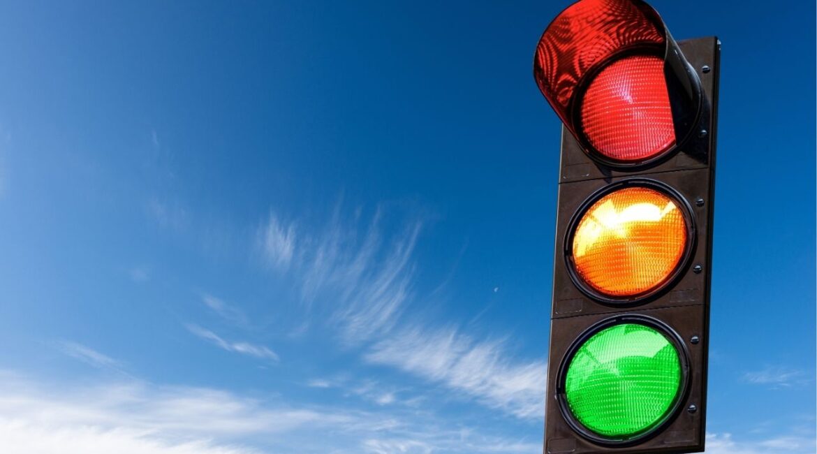 Asset id: 2075708056 Closeup of a traffic light on a blue sky with clouds and copy space, with all three lights on, green, orange and red. Italy, Europe.