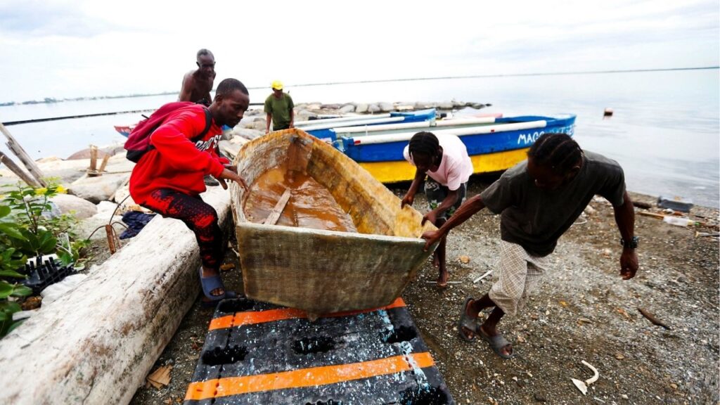 Fishermen lift and secure a small boat along the shoreline as they prepare for the arrival of Tropical Storm Melissa, which is forecast to bring heavy rain and strong winds, in Kingston, Jamaica, October 25, 2025. (Reuters/Octavio Jones)