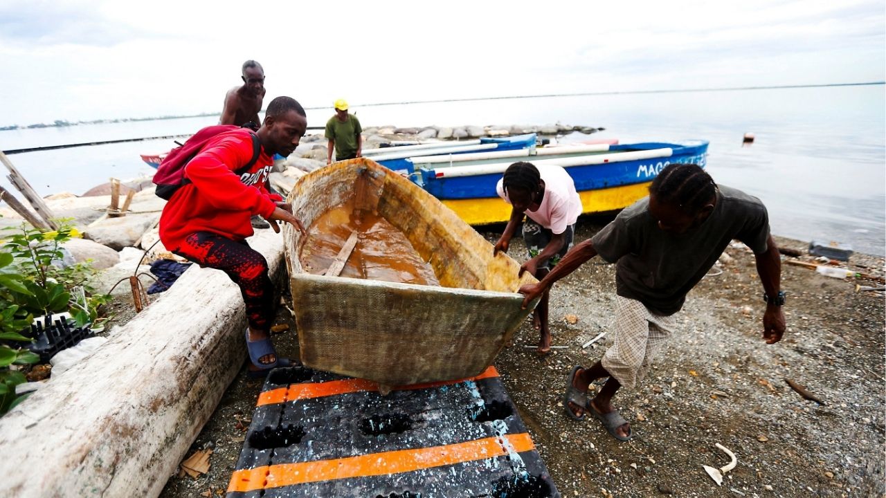 Fishermen lift and secure a small boat along the shoreline as they prepare for the arrival of Tropical Storm Melissa, which is forecast to bring heavy rain and strong winds, in Kingston, Jamaica, October 25, 2025. (Reuters/Octavio Jones)