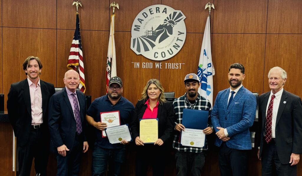Carlos Perea Romero and Angel Zarco standing with Madera County supervisors holding framed awards