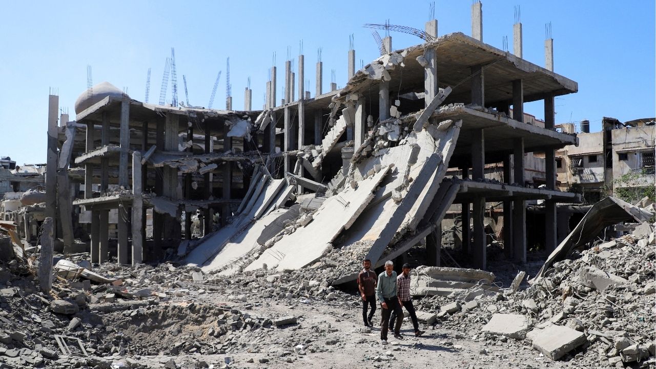Palestinians walk past a destroyed building, as they inspect the damage in the aftermath of Israeli operation at Sabra neighbourhood in Gaza City, October 8, 2025. REUTERS/Ebrahim Hajjaj TPX IMAGES OF THE DAY