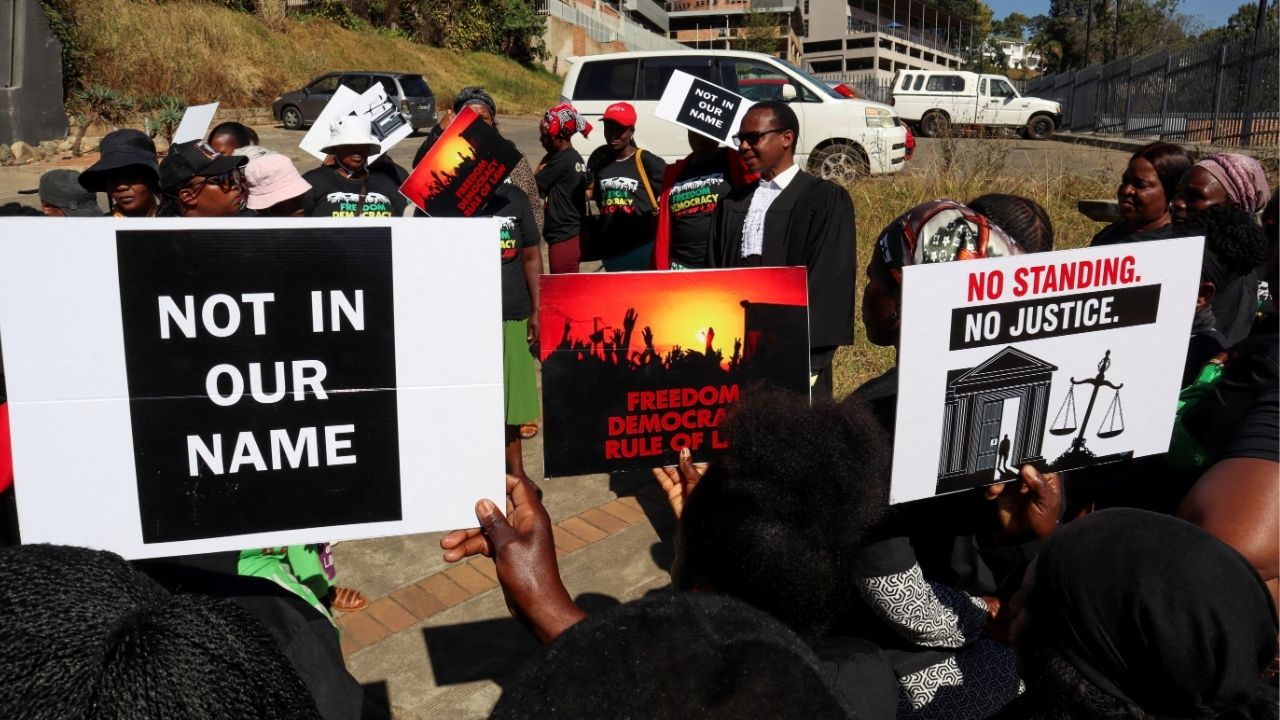 Protesters hold placards as lead applicant and lawyer Mzwandile Masuku addresses them outside the court, after today's hearing was postponed, in Mbabane, Eswatini, August 22, 2025. Activists are challenging a secretive agreement with former U.S. President Donald Trump's administration to accept third-country deportees, which they argue is unconstitutional. (Reuters File)