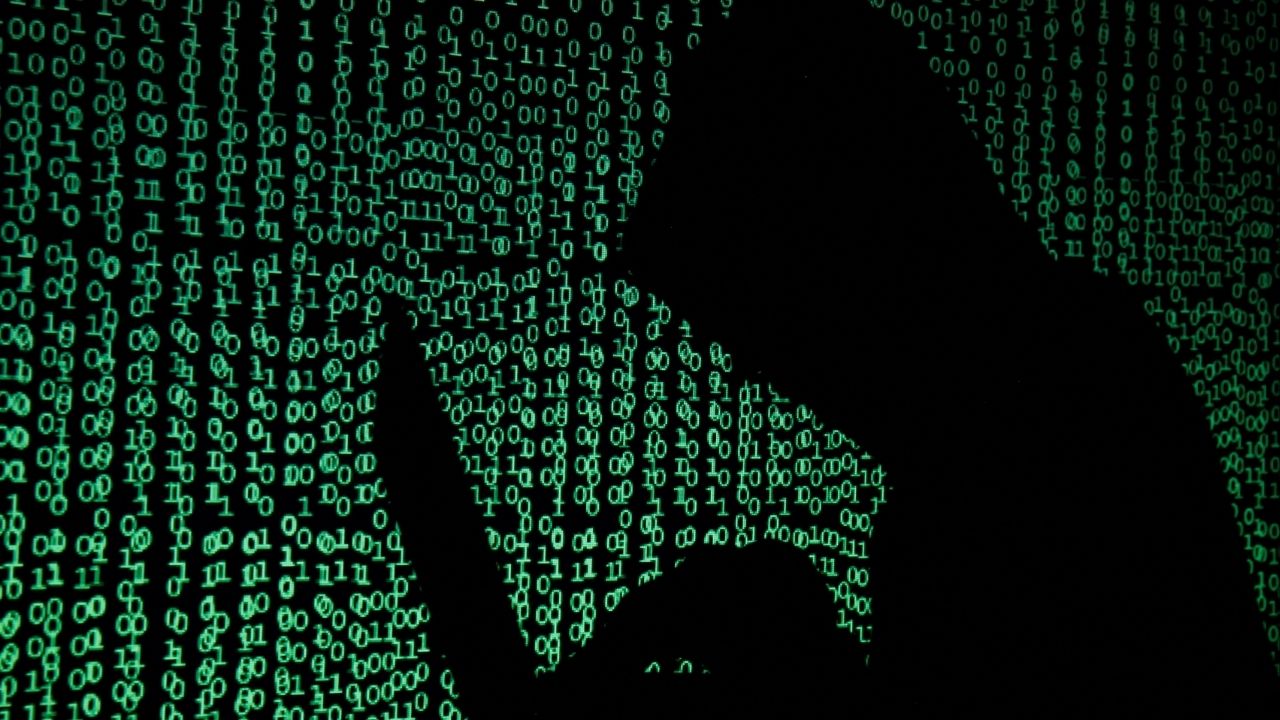 A hooded man holds a laptop computer as cyber code is projected on him in this illustration picture taken on May 13, 2017. (Reuters File)