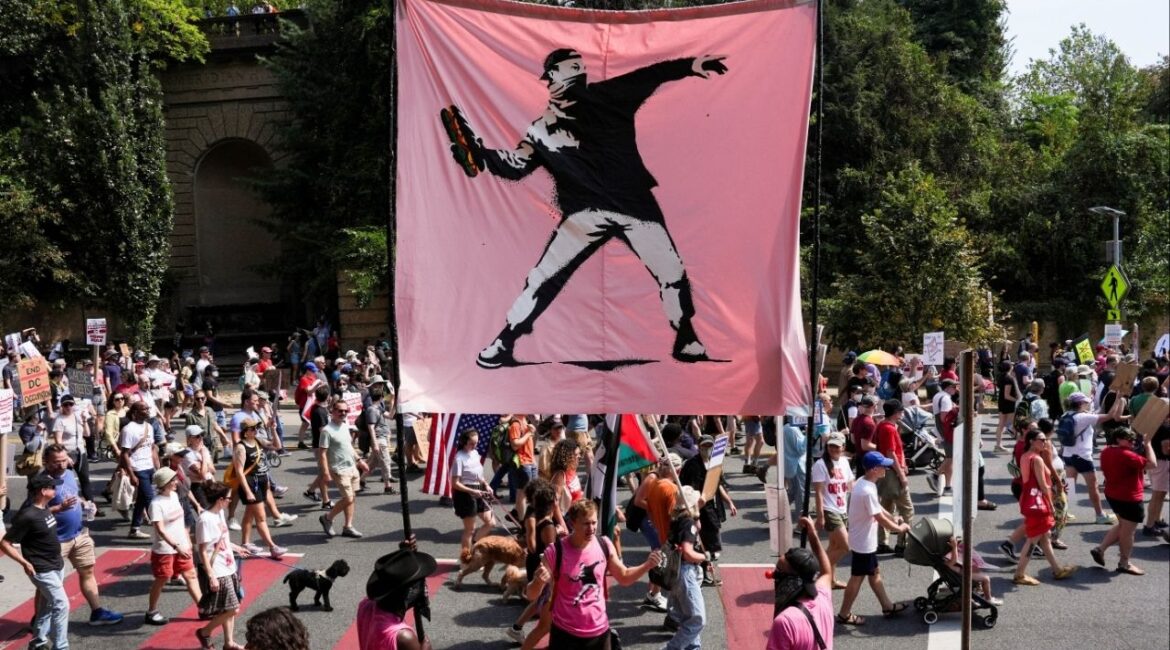 Demonstrators hold a banner inspired by the work of artist Banksy, showing a masked protester throwing a sandwich, as they attend a "We Are All DC" march, in Washington, D.C., U.S., September 6, 2025. (Reuters/Leah Millis)