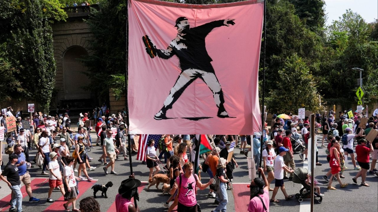 Demonstrators hold a banner inspired by the work of artist Banksy, showing a masked protester throwing a sandwich, as they attend a "We Are All DC" march, in Washington, D.C., U.S., September 6, 2025. (Reuters/Leah Millis)