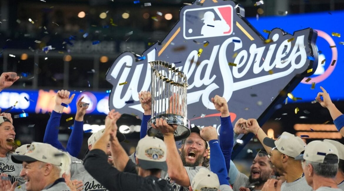 Oct 31, 2025; Toronto, Ontario, CAN; Los Angeles Dodgers pitcher Clayton Kershaw (22) celebrates with the Commissioner's Trophy on the podium after defeating the Toronto Blue Jays in the 2025 MLB World Series at Rogers Centre. (John E. Sokolowski-Imagn Images)