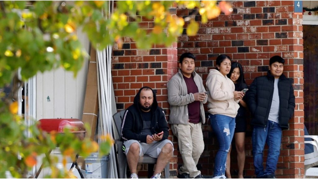 Residents of a largely Hispanic neighborhood watch a gathering of fellow community members and activists across the street from the site of a concluded raid by federal authorities as they expand their crackdown on illegal immigration, in Raleigh, North Carolina, U.S., November 18, 2025. (Reuters/Jonathan Drake)