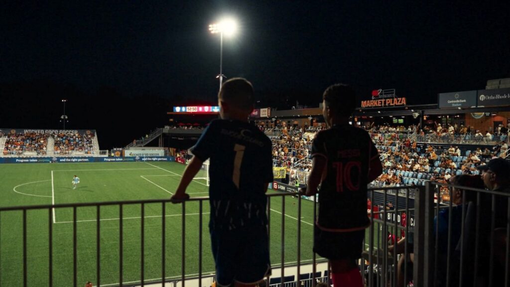 Image of two soccer fans watching a match at Centreville Bank Stadium in Pawtucket, Rhode Island.