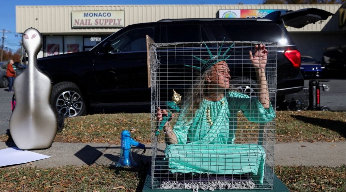 Shana Blake, a protestor wearing a Statue of Liberty outfit sits in a cage, as Members of the Customs and Border Patrol (CBP) conduct immigration raids on the streets of Charlotte, North Carolina, U.S., November 17, 2025. (Reuters/Sam Wolfe)