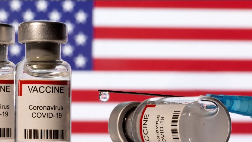 Vials labelled "VACCINE Coronavirus COVID-19" and a syringe are seen in front of a displayed U.S. flag in this illustration taken December 11, 2021. REUTERS/Dado Ruvic/Illustration