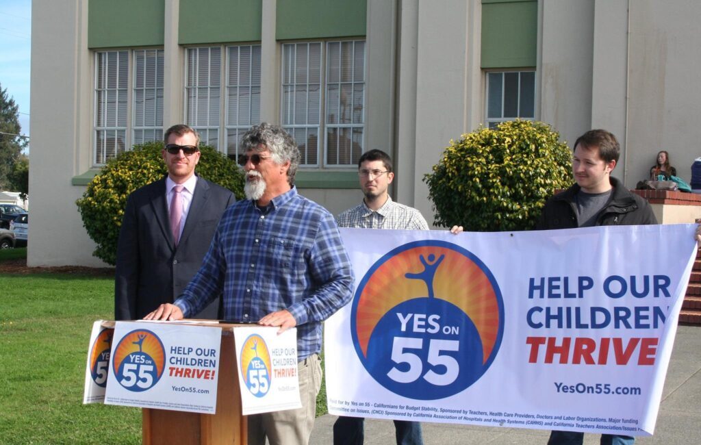 Image of Prop 55 Supporters Holding up Yes on 55 Banners