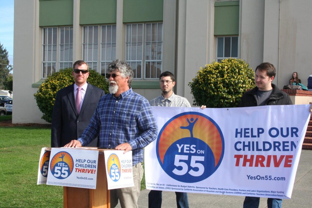 Image of Prop 55 Supporters Holding up Yes on 55 Banners