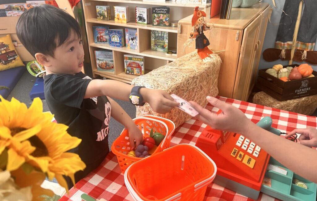 a Clovis Unified preschooler buys groceries at the pretend farmers market in the district’s hands-on interactive farm exhibit, which is meant to engage students in dramatic play, a form of arts education.