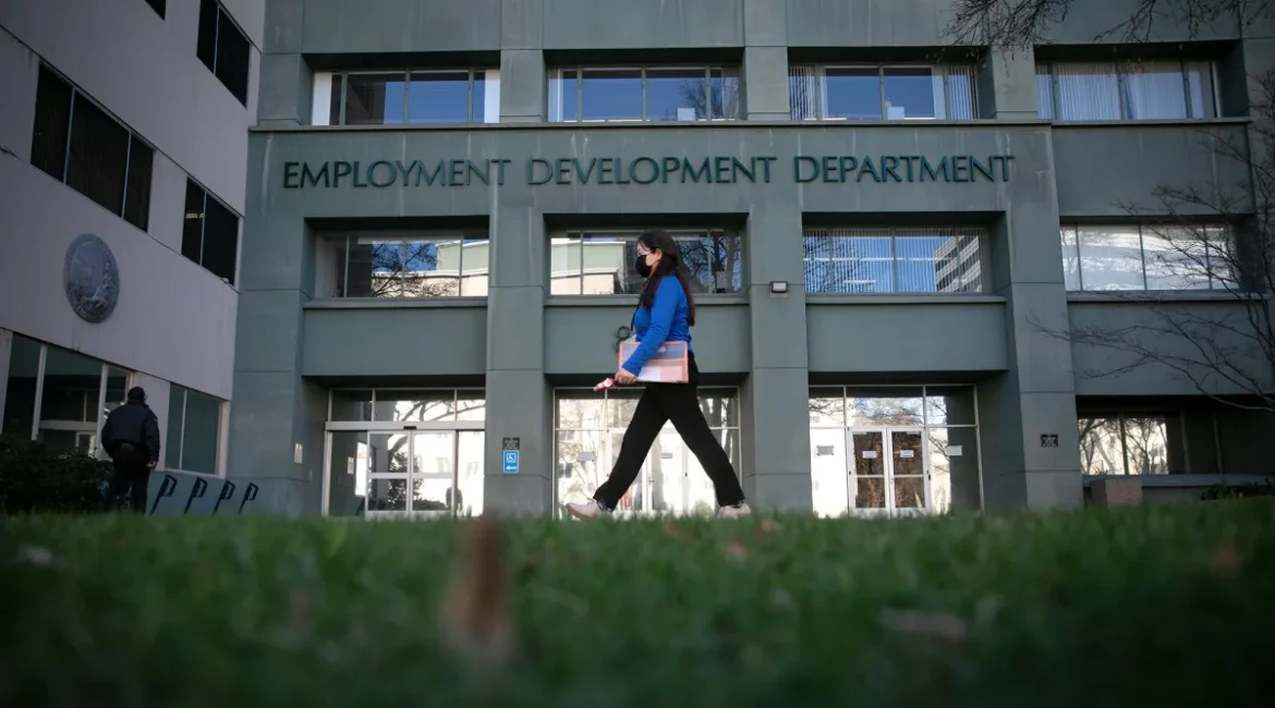 Image of woman in a blue top and black pants walking in front of the state Employment Development Department in Sacramento on a winter day.