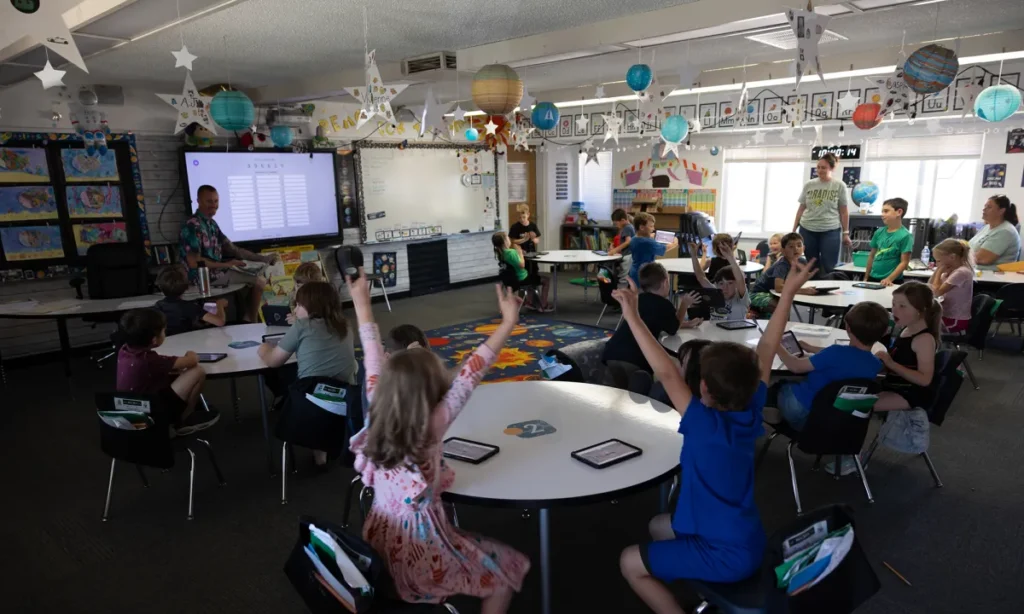 Image of school children raising their hands in a festive classroom