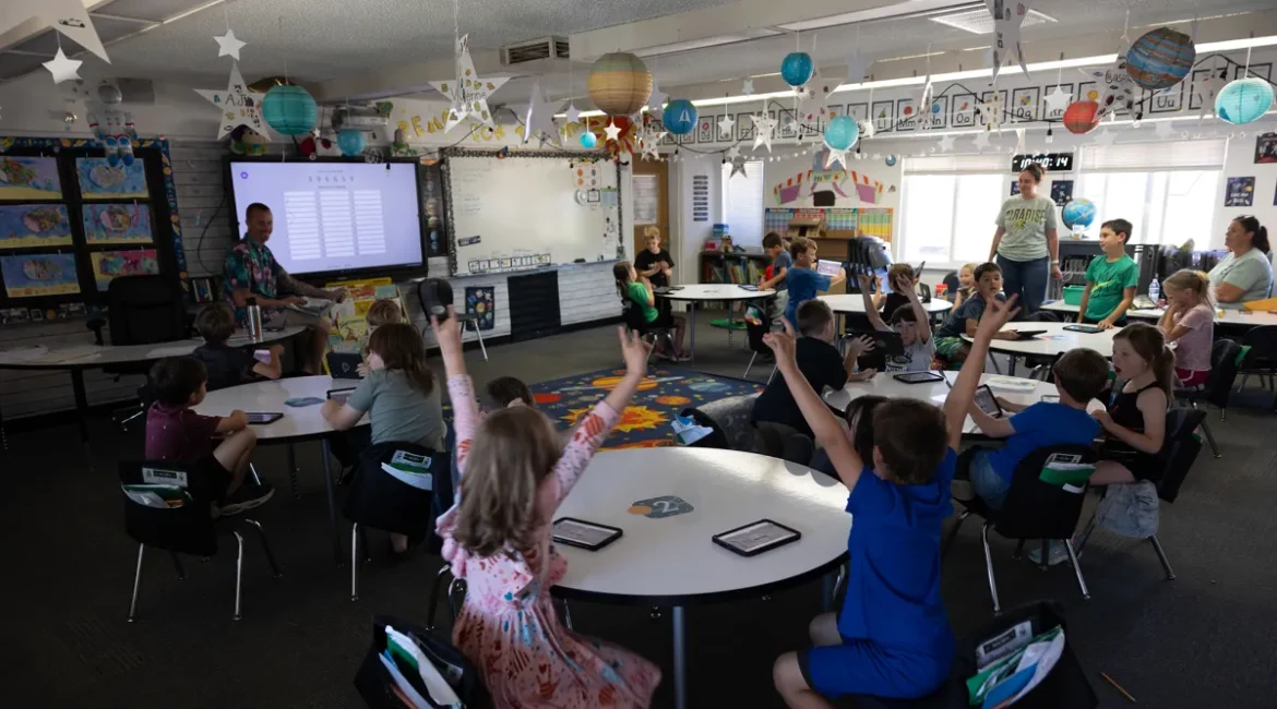 Image of school children raising their hands in a festive classroom
