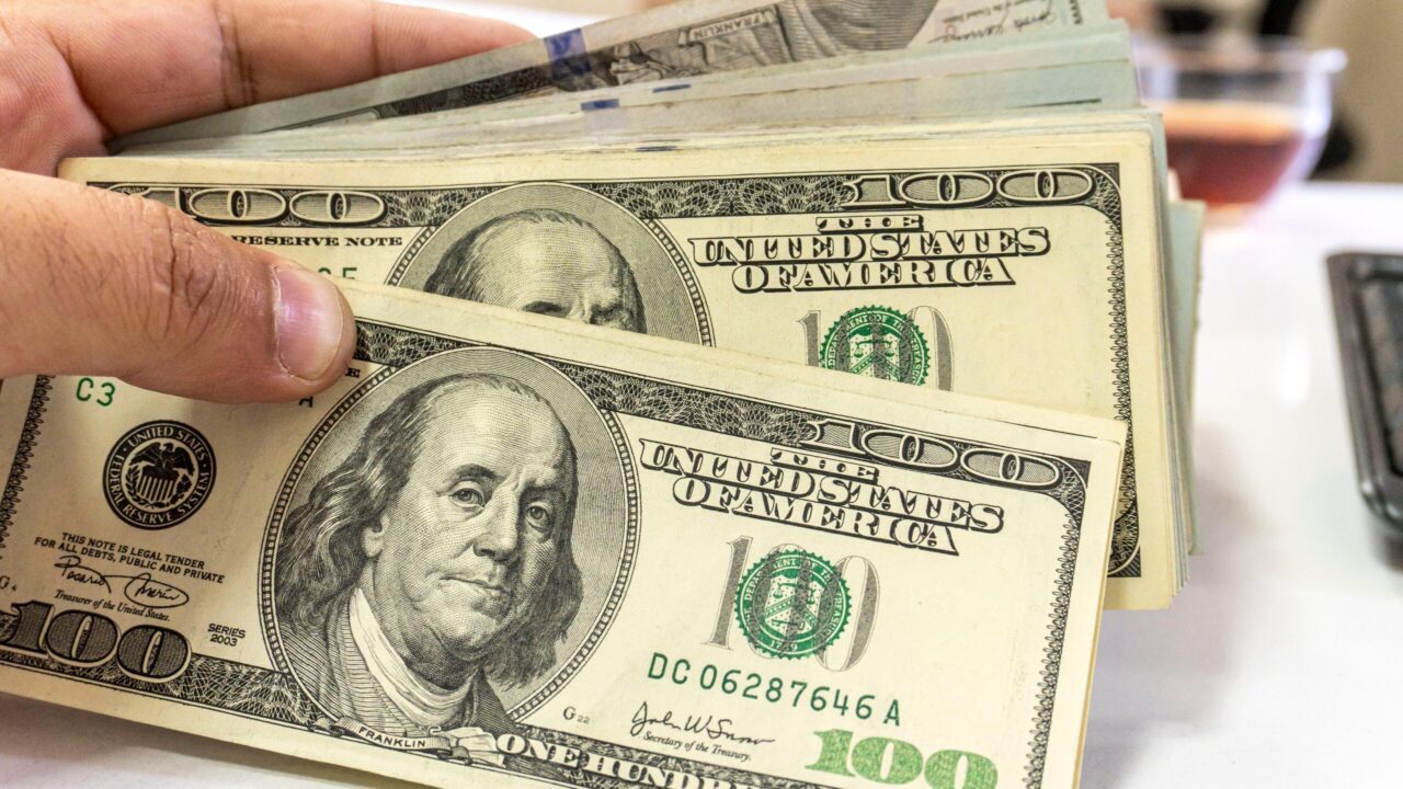 Image of a hand fanning out a stack of $100 bills