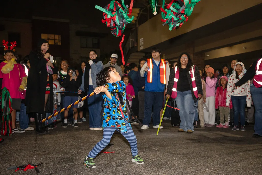 Image of a child swinging at a pinata during a Latino Christmas party. 