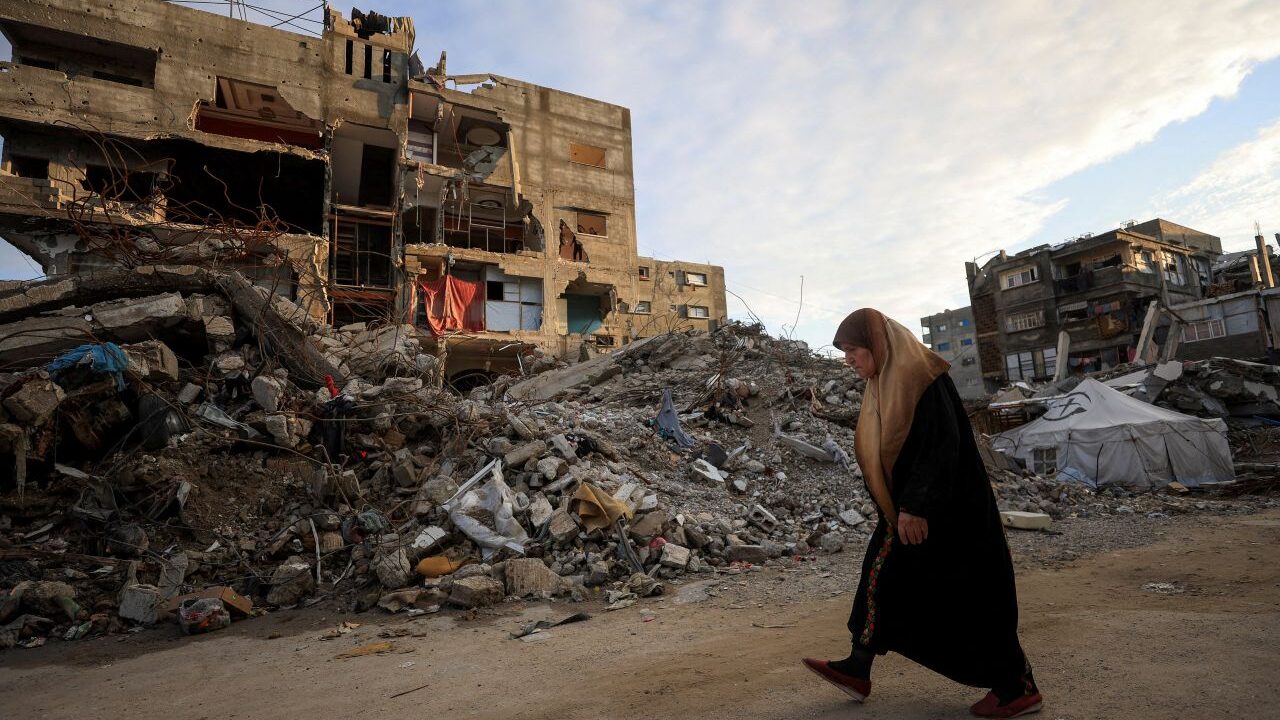 Image of a Palestinian woman walking amid the ruins in Gaza City.