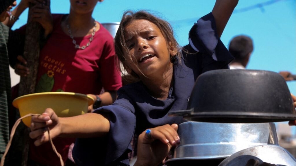 A Palestinian girl gestures as she waits to receive food from a charity kitchen, amid a hunger crisis, in Khan Younis, southern Gaza Strip, August 4, 2025. (Reuters/Hatem Khaled)