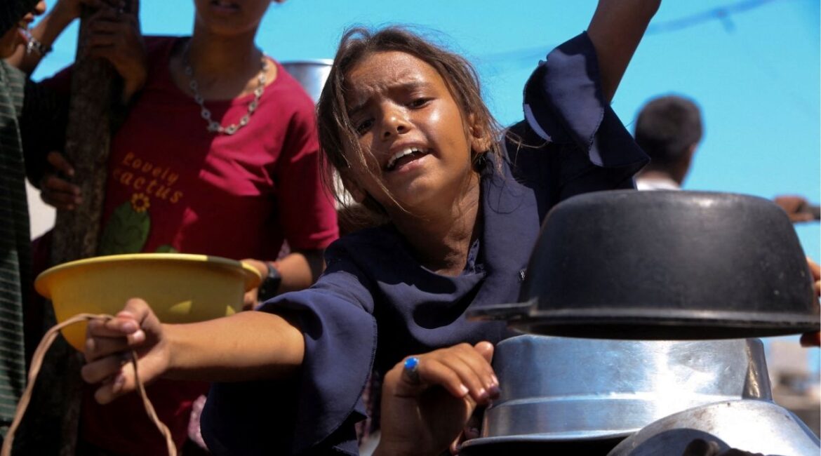 A Palestinian girl gestures as she waits to receive food from a charity kitchen, amid a hunger crisis, in Khan Younis, southern Gaza Strip, August 4, 2025. (Reuters/Hatem Khaled)