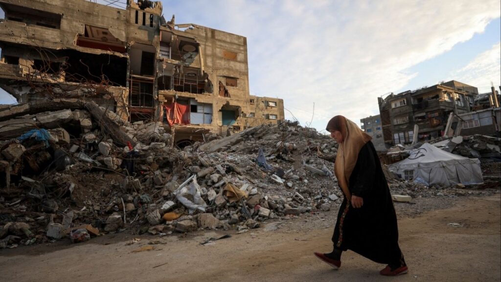A Palestinian woman walks past residential buildings damaged and destroyed during the war, in Gaza City, December 14, 2025. (Reuters File)