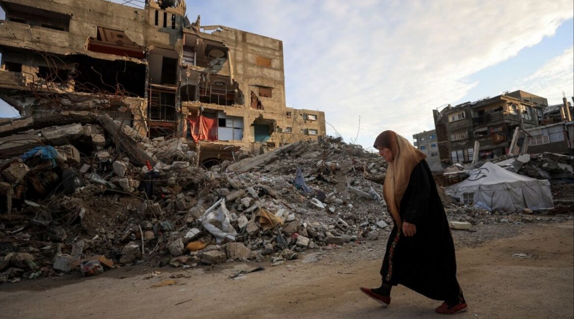 A Palestinian woman walks past residential buildings damaged and destroyed during the war, in Gaza City, December 14, 2025. (Reuters File)