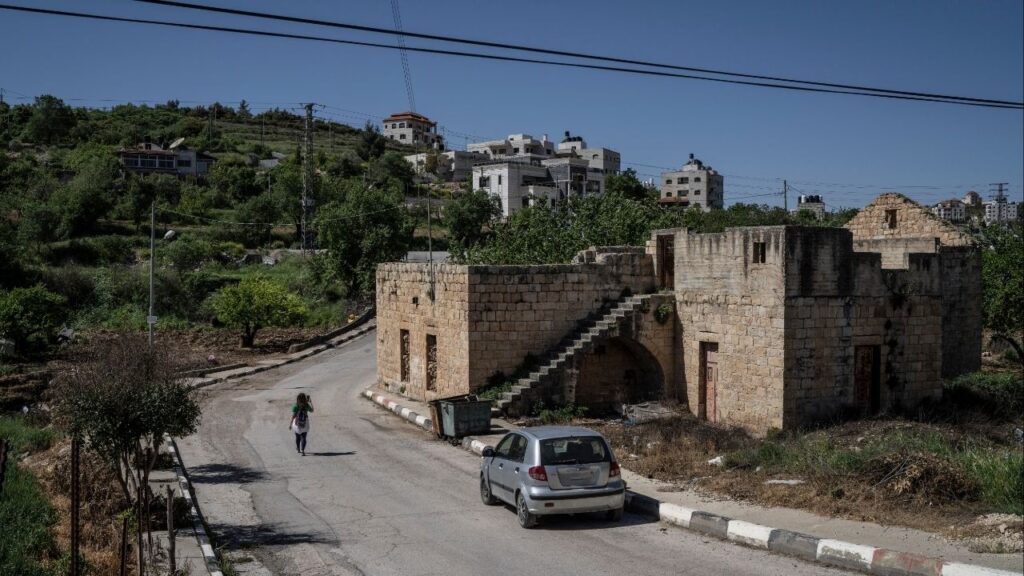 A Palestinian woman with a group of unseen other hikers walks along a road on the outskirts of the West Bank city of Ramallah, April 18, 2025. With Israelis rapidly building in the West Bank, Palestinian hikers are increasingly unable to safely walk across the land. (Samar Hazboun/The New York Times)