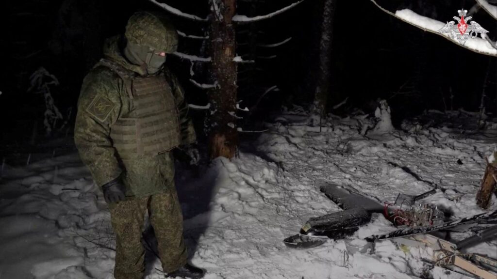 A Russian service member stands next to the remains of a drone, which, according to the Russian Defence Ministry, was downed during the repelling of an alleged Ukrainian attack on the Russian presidential residence in the Novgorod Region, in an unknown location in Russia, in this still image from a video released December 31, 2025. Russian Defence Ministry/Handout via REUTERS