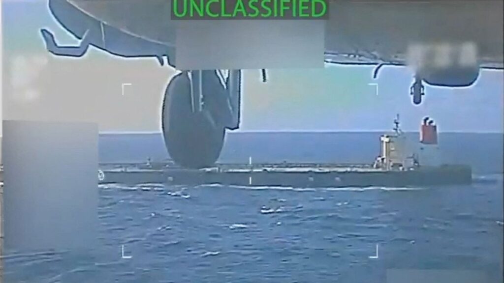 A U.S. military helicopter flies near an oil tanker during a raid described by U.S. Attorney General Pam Bondi as its seizure by the United States off the coast of Venezuela, December 10, 2025, in a still image from video. (U.S. Attorney General/Handout via Reuters)