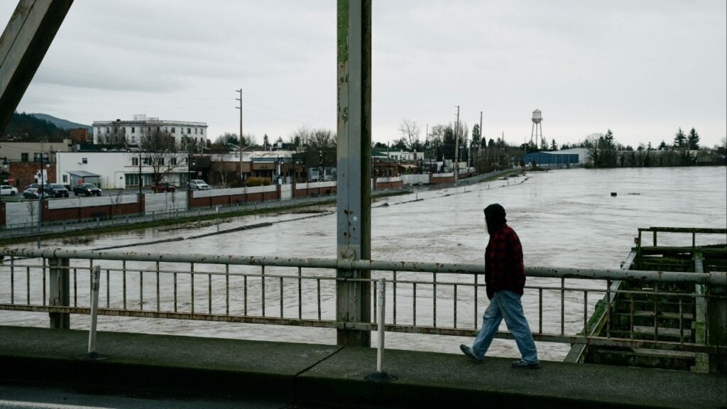 A man crosses the Division Street Bridge as the rising Skagit River passes near downtown Mount Vernon, Wash., on Thursday, Dec. 11, 2025. The river is forecast to crest on Friday morning after several days of heavy rain pushed waterways in the region to record levels. (Grant Hindsley/The New York Times)