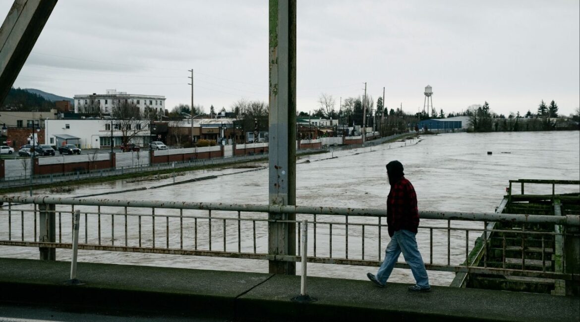 A man crosses the Division Street Bridge as the rising Skagit River passes near downtown Mount Vernon, Wash., on Thursday, Dec. 11, 2025. The river is forecast to crest on Friday morning after several days of heavy rain pushed waterways in the region to record levels. (Grant Hindsley/The New York Times)