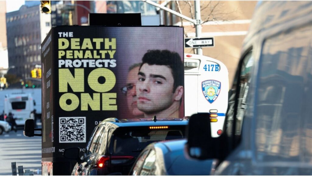 A screen displays a picture of Luigi Mangione, the suspect in the killing of UnitedHealthcare chief executive Brian Thompson, ahead of his appearance for a pre-trial hearing on murder charges, in New York City, New York, U.S., December 1, 2025. (Reuters/Mike Segar)
