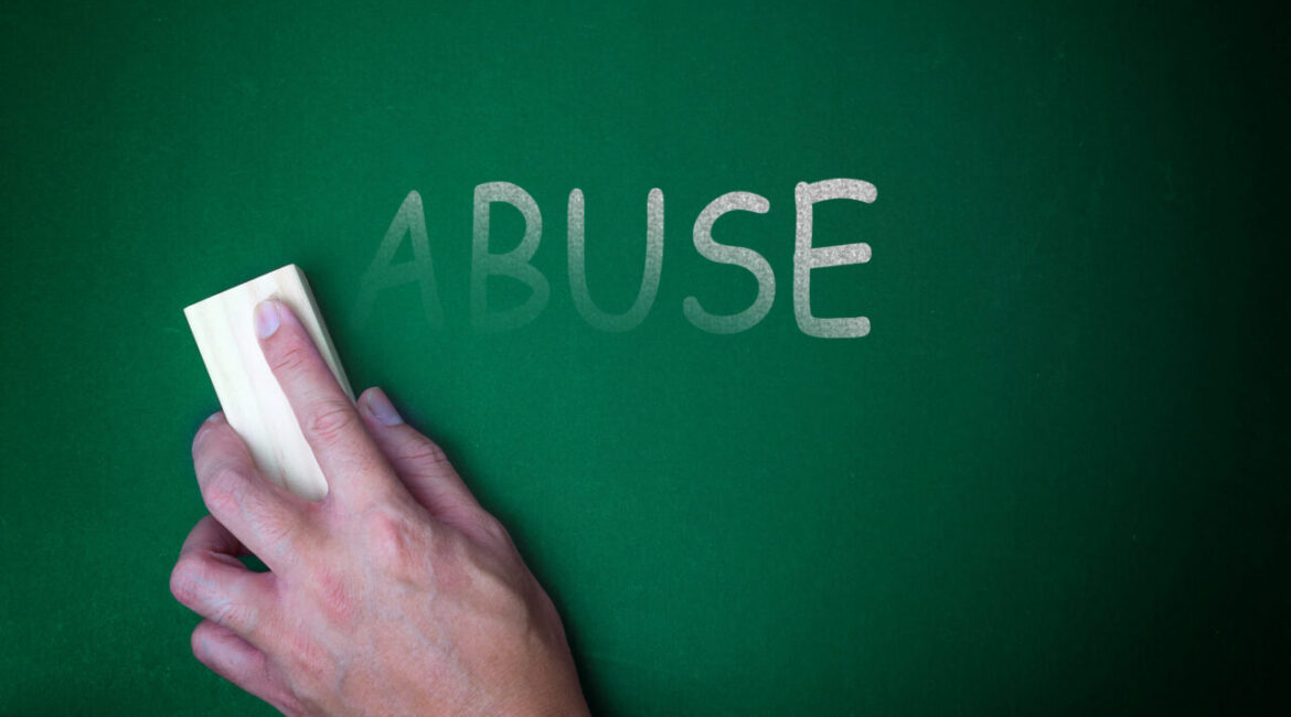 Image of a hand holding an eraser wiping away the word "Abuse" on a green chalkboard